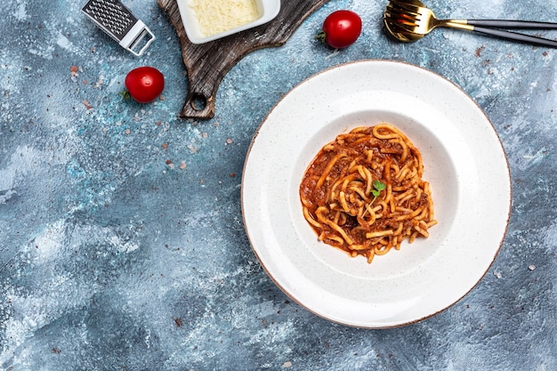 伝統的なイタリアのスパゲッティボロネーゼとトマトとミートミンチソースをパルメザンチーズと一緒に皿に盛り付けます。バナー、メニュー、テキストのレシピの場所、上面図。