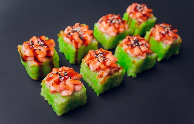 Traditional japanese food Mix colorful sushiSet of different kinds of sushi rolls with salmon shrimp and vegetables On black rustic background Top view