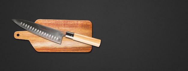 Traditional Japanese gyuto chief knife on a cutting board. Black banner background