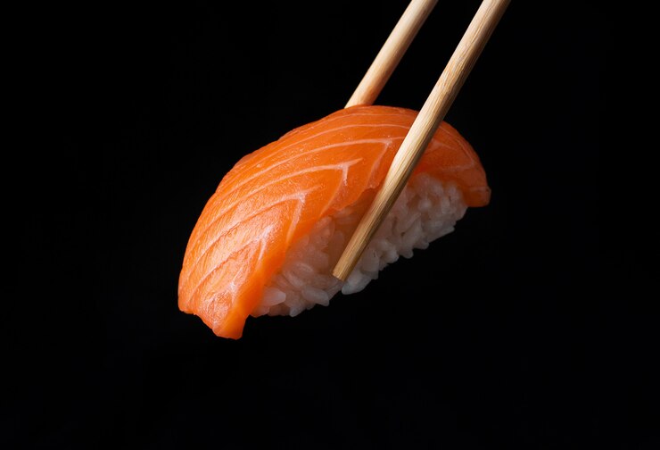 Photo traditional japanese nigiri sushi with salmon placed between chopsticks