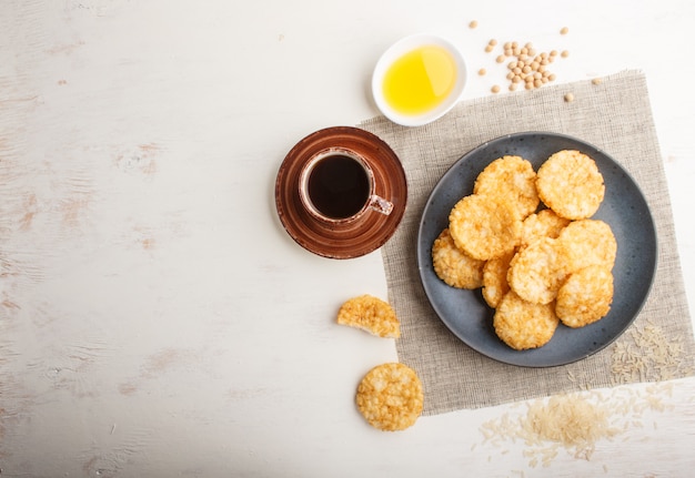 Traditional japanese rice chips cookies with honey and soy sauce on a blue ceramic plate and a cup of coffee 