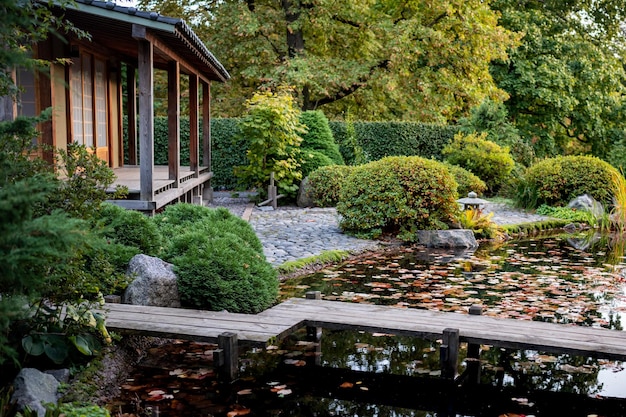 写真 池のある伝統的な日本の茶屋石と緑の茂みのある木製の橋の庭