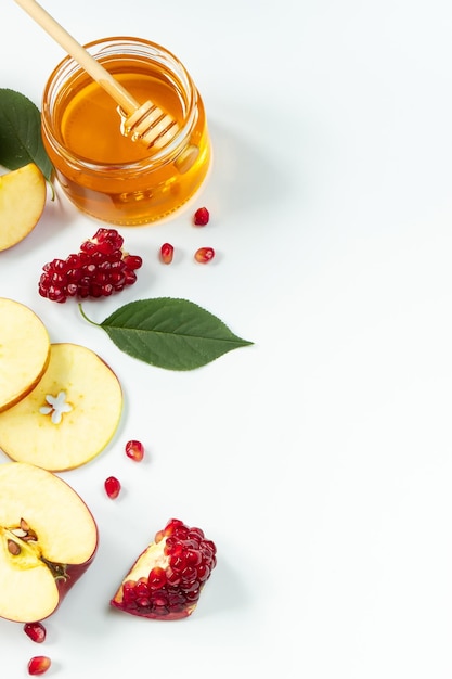 Traditional Jewish holiday New Year Happy Rosh Hashanah Apples pomegranates and honey on white background Vertical photo