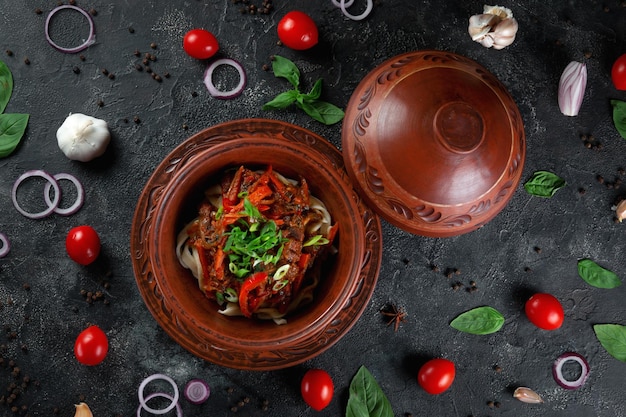 Traditional Kazakh dish Kuirdak Aromatic roast of byproducts lamb meat with lots of onions and vegetables in a clay pot