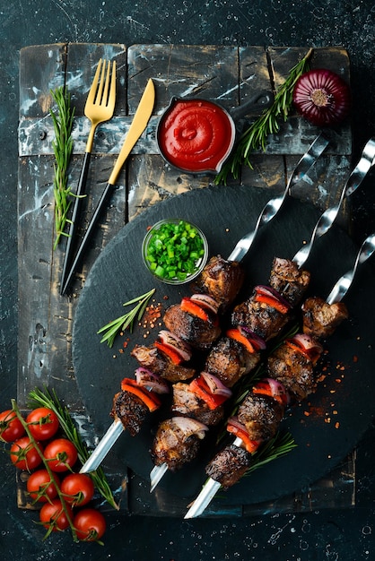 Traditional Kebab Juicy pork skewers with vegetables on a black stone plate Barbecue Top view Free space for text