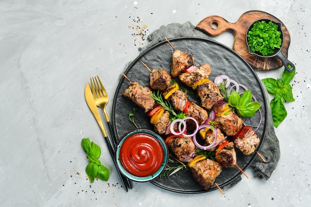 Traditional Kebab Juicy pork skewers with vegetables on a black stone plate Barbecue Top view Free space for text