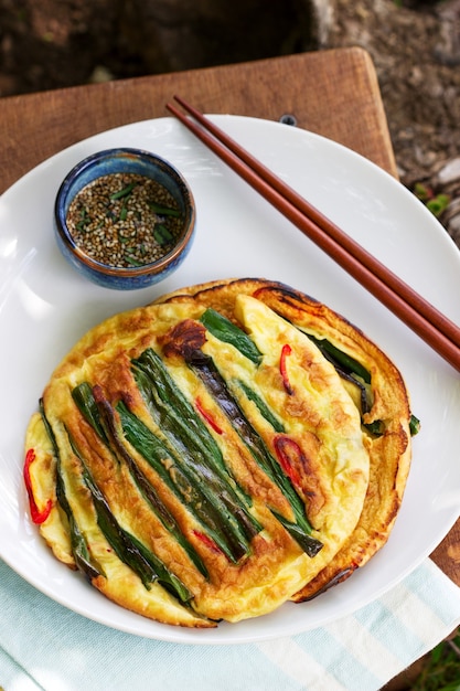 Photo traditional korean fritters with green onions and chili, served with soy sauce.