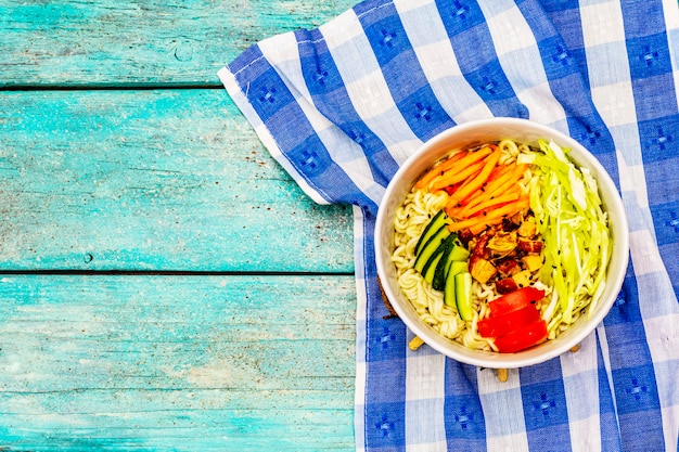 Traditional Korean noodle bowl with smoked chicken, fresh sliced vegetables and sesame seeds