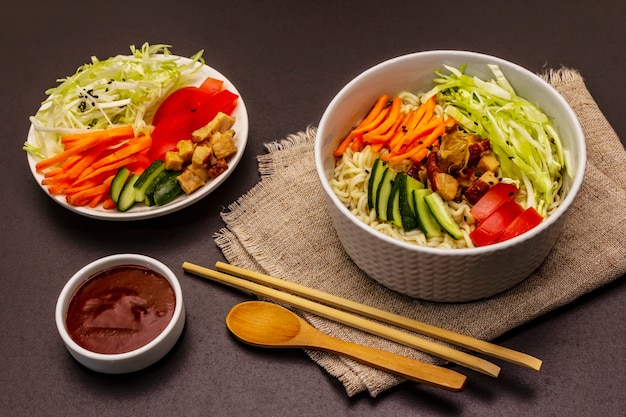 Traditional Korean noodle bowl with smoked chicken, fresh sliced vegetables and sesame seeds