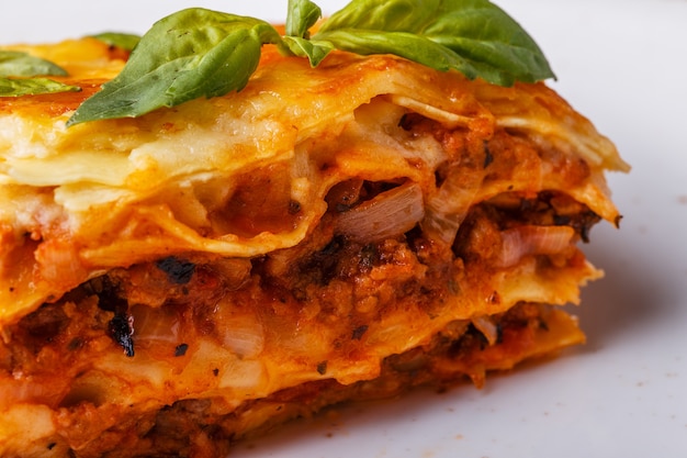 Traditional lasagna made with minced beef bolognese sauce and bechamel sauce  topped with basil leafs.