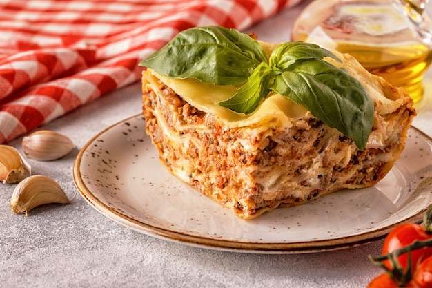 Traditional lasagna made with minced beef bolognese sauce and bechamel sauce topped with basil leaves.