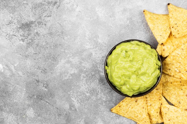 Photo traditional latin american sauce guacamole in a bowl and nachos.