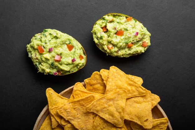 Guacamole di salsa latinoamericana tradizionale in patatine fritte di nachos messicane di avocado tagliato a metà