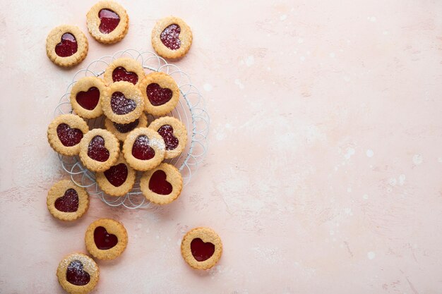 분홍색 아름다운 배경에 딸기 잼과 가루 설탕을 넣은 전통적인 린저 쿠키 상위 뷰 발렌타인 데이 휴일 스낵 컨셉의 전통적인 홈메이드 오스트리아 달콤한 디저트 음식