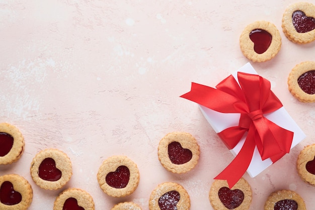 Traditional Linzer cookie with strawberry jam and powder sugar gift and red ribbon on pink beautiful background Top view Traditional homemade Austrian sweet dessert food on Valentines Day