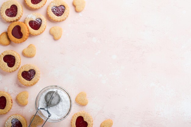 Traditional Linzer cookie with strawberry jam and powder sugar on pink beautiful background Top view Homemade Austrian sweet dessert food on Valentines Day Holiday snack concept