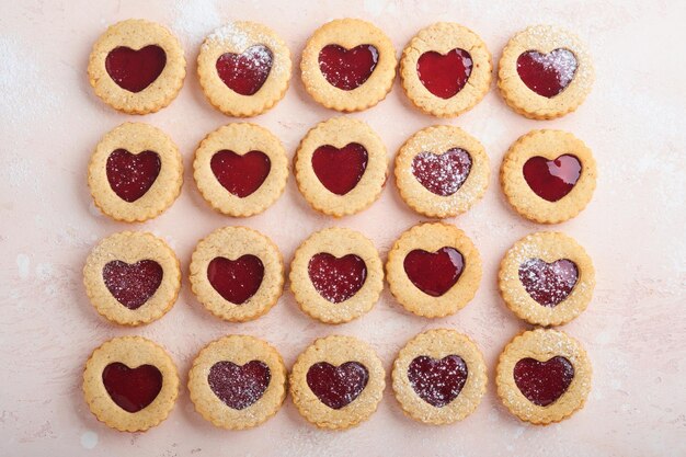 Traditional Linzer cookie with strawberry jam and powder sugar on pink beautiful background Top view Traditional homemade Austrian sweet dessert food on Valentines Day Holiday snack concept