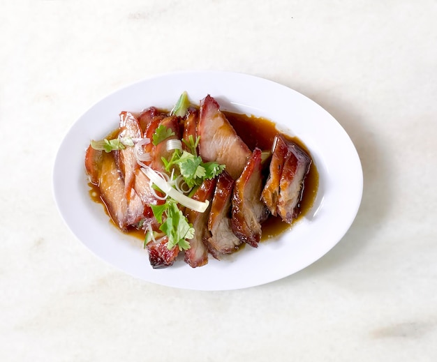 Traditional local style Char Siu or Char Siew Honey barbecue roast pork on white plate of marble t