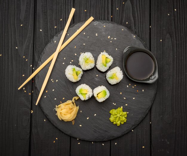 Традиционные маки суши роллы с авокадо на черной тарелке