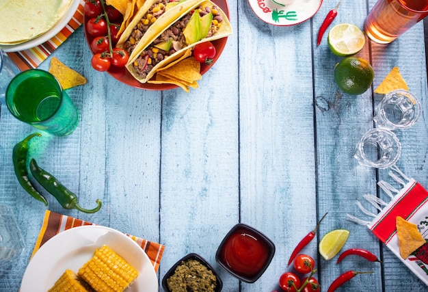 Traditional Mexican corn tacos with meat vegetables avocado beans salsa and nachos Served with various sauces and drinks Top view Big family gatherings