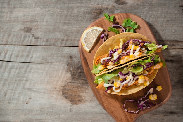 Traditional mexican taco with chicken and vegetables on wooden table. Latin american food.