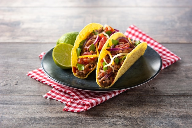 Traditional Mexican tacos with meat and vegetables on wooden table