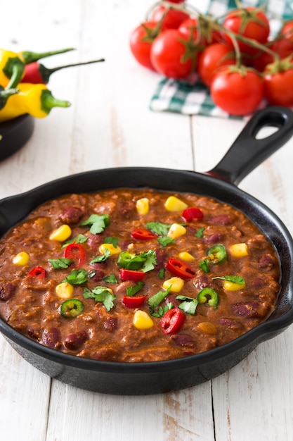 Traditional mexican tex mex chili con carne in a frying pan on white wooden table