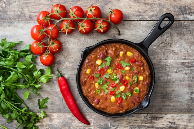 Traditional mexican tex mex chili con carne in a frying pan on wooden table