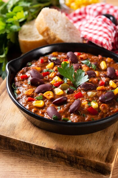 Traditional mexican tex mex chili con carne in iron pan on wooden table