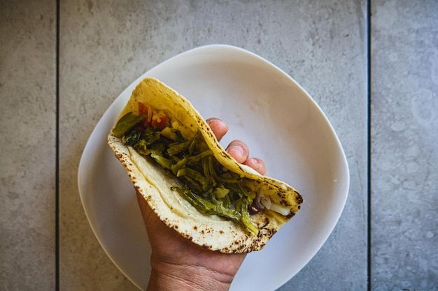 Traditional mexican tortilla with nopales opuntia in hand on the table