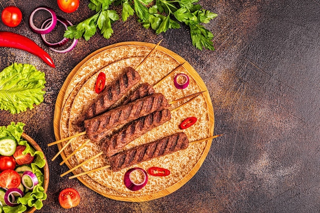 Традиционный ближневосточный, арабский или средиземноморский мясной шашлык с овощами и лаваш-хлебом. Вид сверху.