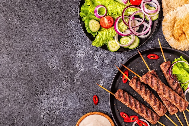 Traditional middle eastern, arabic or mediterranean meat kebab with vegetables and pita bread. Top view.