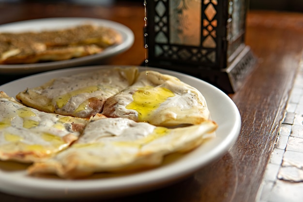 Traditional Middle Eastern food. Lebanese. Arabian cuisine. Manakish, pouring olive oil, lamp