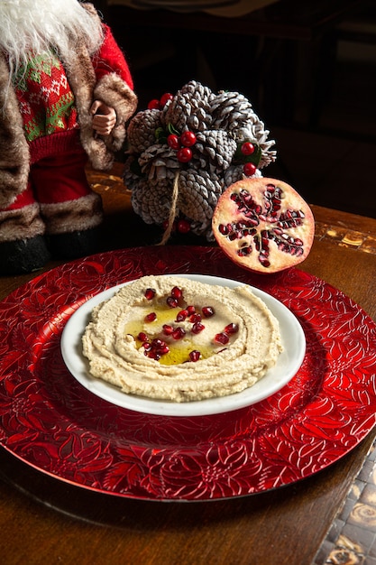 Photo traditional middle eastern food. lebanese food. arabian hummus with pomegranate seeds and christmas decoration