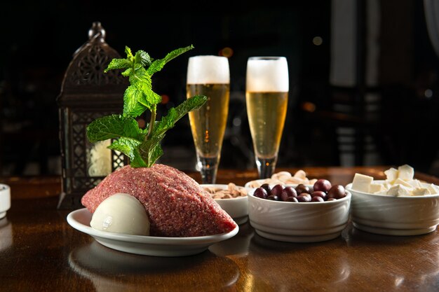 Foto cibo tradizionale mediorientale. cibo libanese. kibbeh arabo crudo, olive, formaggio, bicchiere di birra