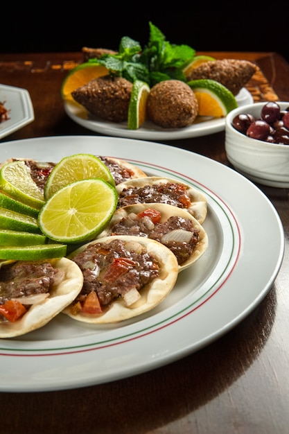 Photo traditional middle eastern food. lebanese sfiha meat. arabian sfeeha plate. esfiha with lemons. kibbeh kibe