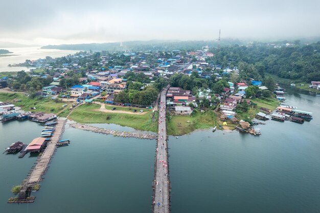 Traditional Mon village in morning foggy and wooden Mon bridge in the dam at Sangkhlaburi