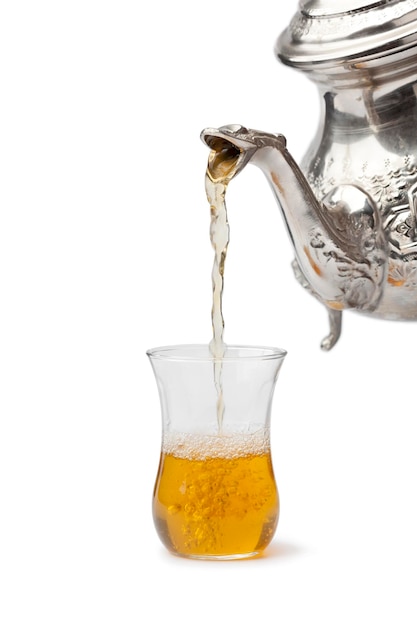 Traditional Moroccon mint tea poured in a glass on white background close up