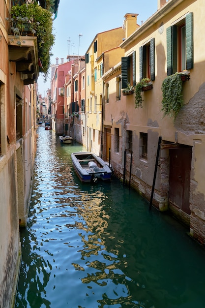 Traditional narrow canal with boats in Venice, Italy. Summer