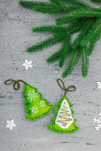 Traditional New Year compositionFestive handmade decor felt Christmas trees embroidered with a cross Holiday time textured gray background place for text