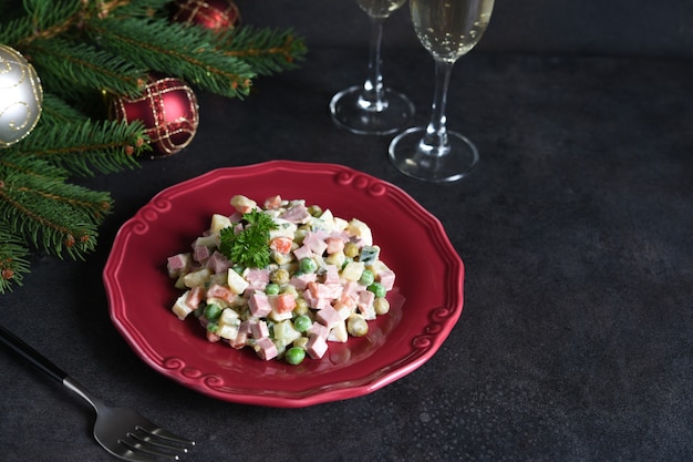 Insalata tradizionale di capodanno olivier. tavola festiva di capodanno e bicchieri di champagne.