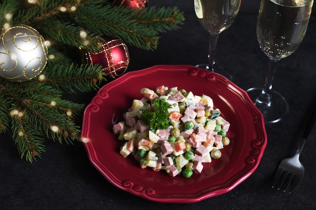 Insalata tradizionale di capodanno olivier. tavola festiva di capodanno e bicchieri di champagne.