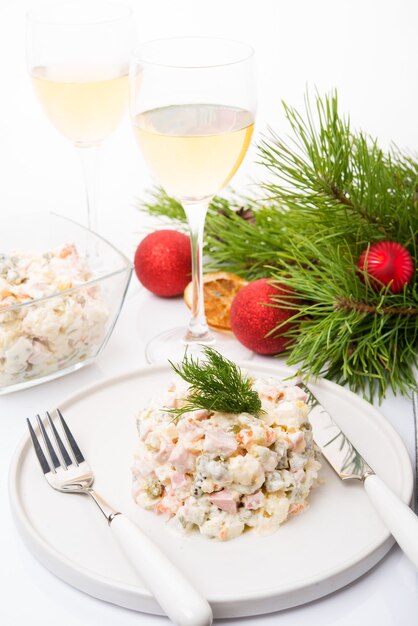 Traditional New Year's salad olivier with festive decorations on a white background, close-up