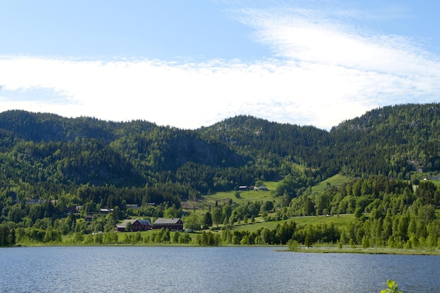 遠くの湖畔と山々に立つ伝統的なノルウェーの木造住宅