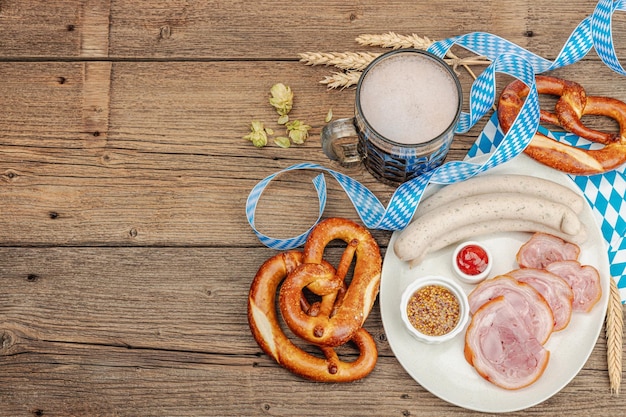 Traditional Oktoberfest set Pretzels beer weisswurst and eisbein with mustard German festival food concept Trendy wooden background top view