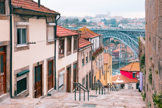 포르투갈 포르투(Porto)의 배경에 있는 리베이라(Ribeira)의 전통 가옥과 도우로(Douro) 강, 돔 루이스 1세(Dom Luis I) 또는 루이스 1세 철교로 내려가는 계단