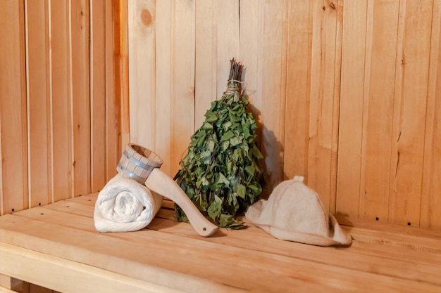 Traditional old Russian bathhouse SPA Concept. Interior details Finnish sauna steam room with traditional sauna accessories set towel birch broom scoop felt. Relax country village bath concept.