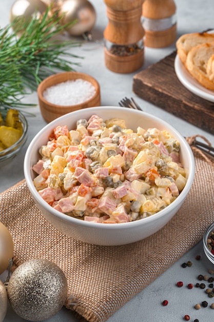 Insalata olivier tradizionale di verdure e salsiccia su sfondo grigio. vista laterale, verticale.