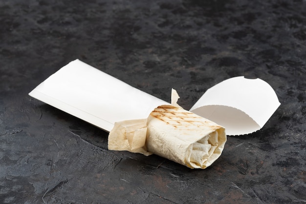 Shawarma orientale tradizionale in cartone ecologico. superficie di pietra scura. concetto di eco pacchetti di riciclabili. copia spazio