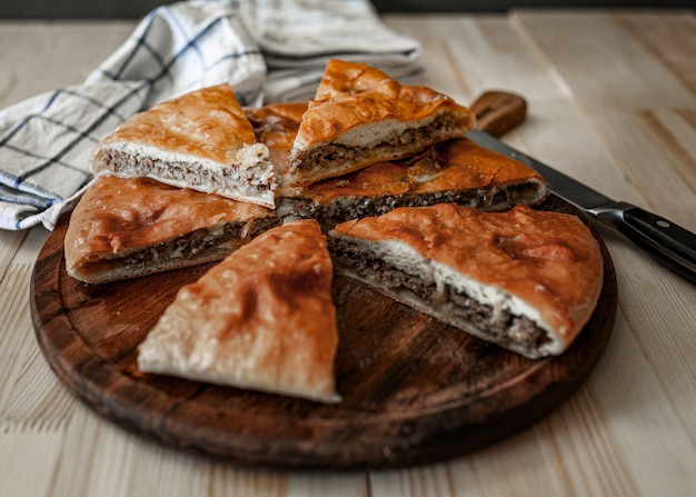 Traditional Ossetian meat pies with beef, on a wooden table. Rustic style, close up, selective focus